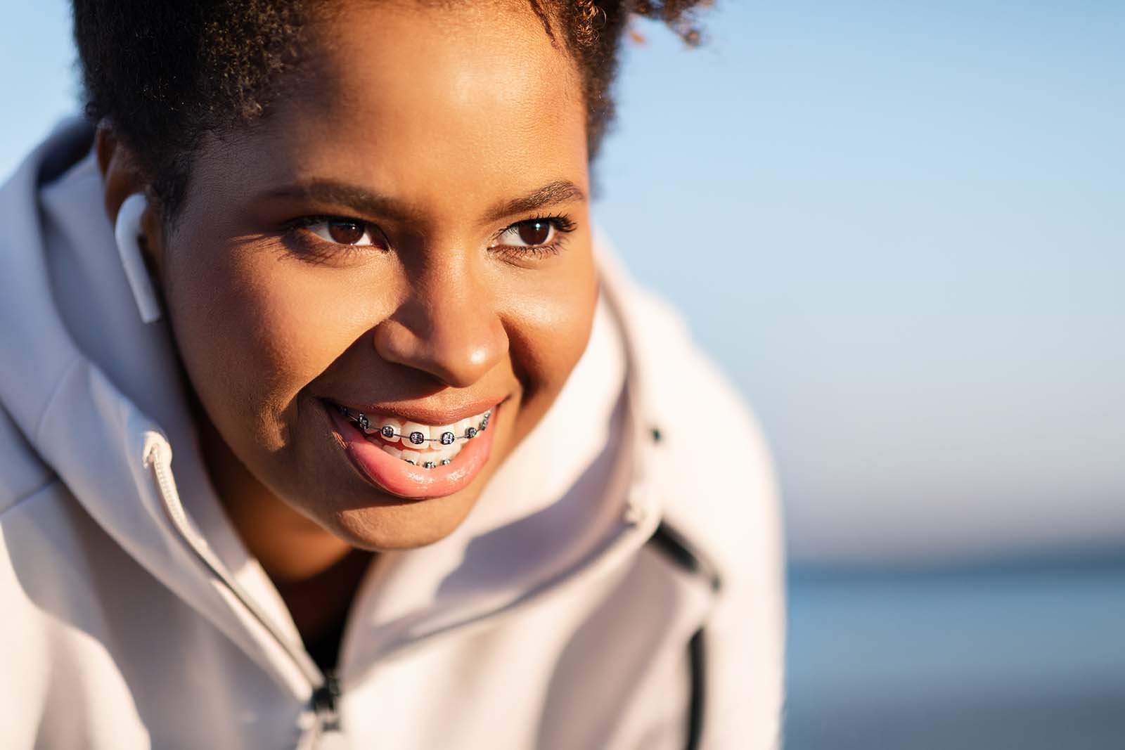 Straight teeth are easier to clean, and support healthier gums and bite smiling young woman with braces exercising at the beach