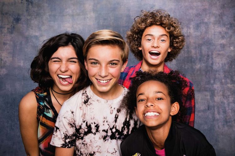 A group of children in a photobooth all smiling and making silly faces after getting Invisalign First treatment from Align Technology.