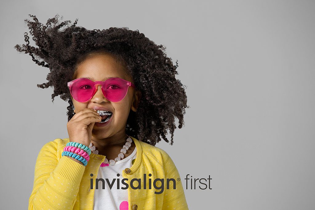 Teen girl smiling with metal braces. Compare Invisalign vs braces for straighter teeth.