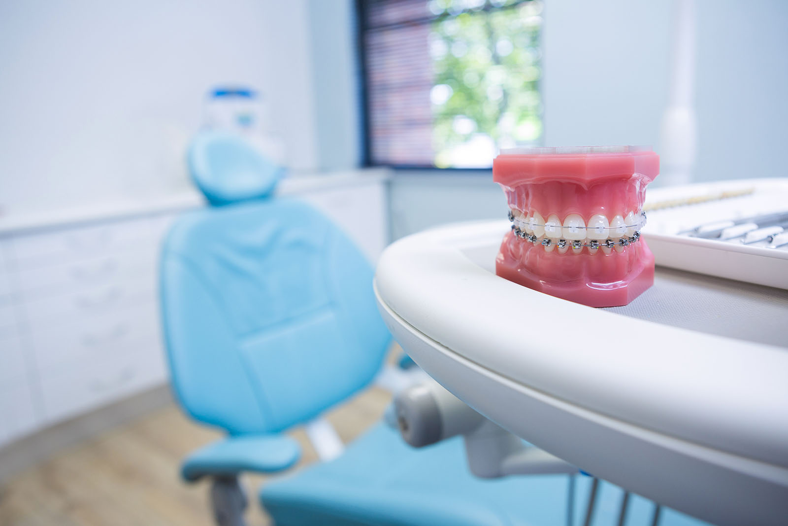 An orthodontist is a specialist that treats certain types of dental problems orthodontic teeth model with braces next to patient chair