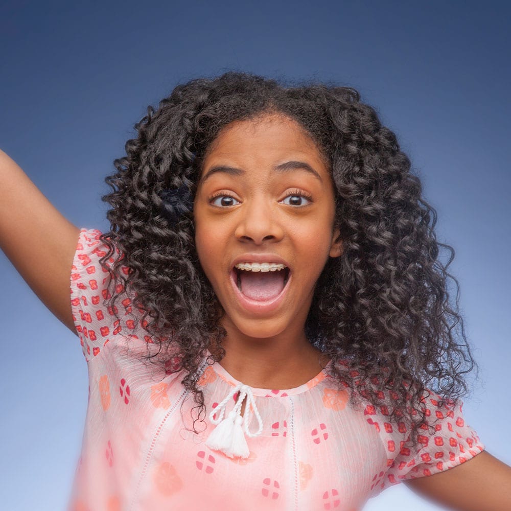 young girl wearing clear braces on her teeth