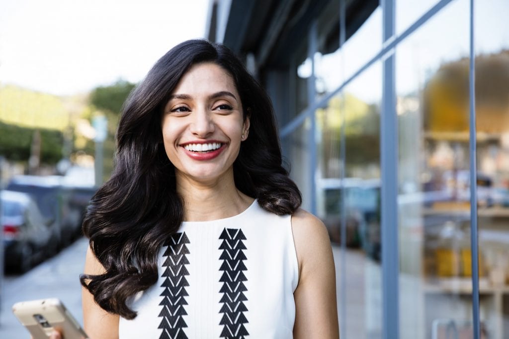 Professional woman walking in city straightening her teeth with Invisalign