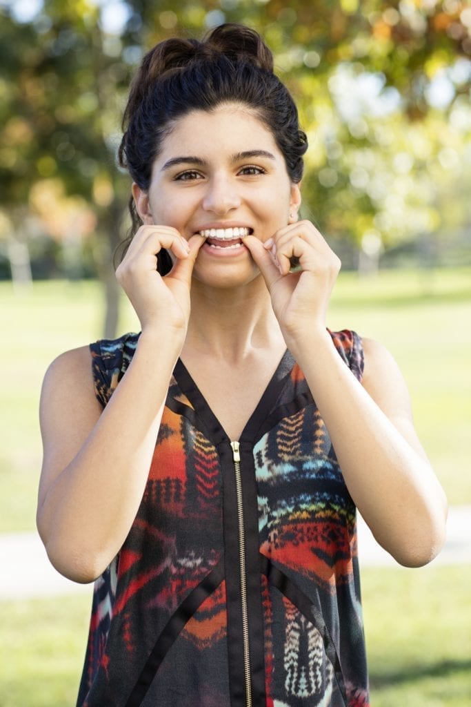 teen girl inserting Invisalign Teen aligner