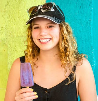 teen girl wearing braces with a popsicle