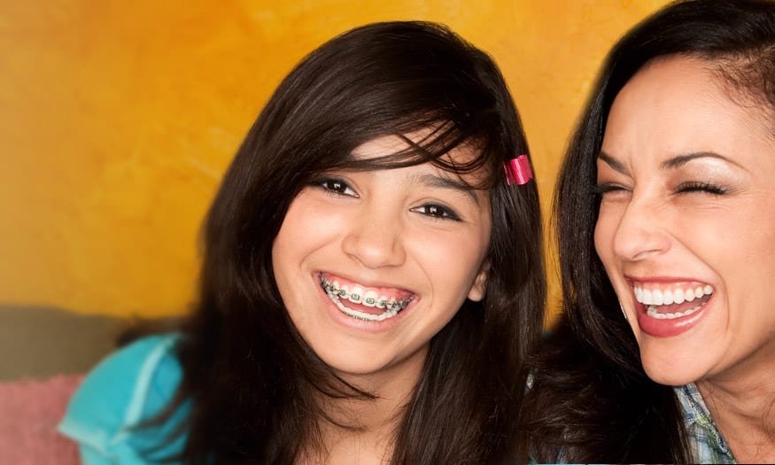 young girl wearing braces and smiling with her mother in sacramento, ca