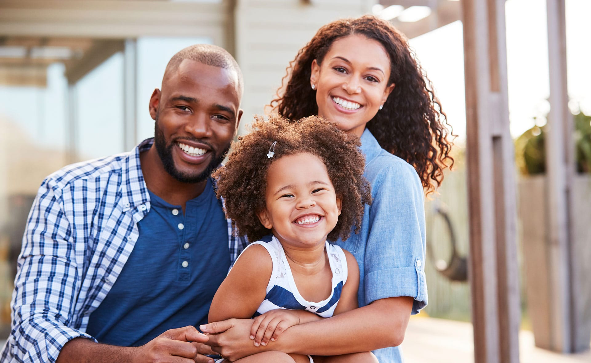 young family embracing outdoors and smiling