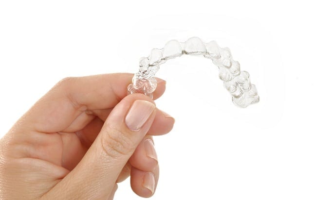 close up of hand holding a clear aligner