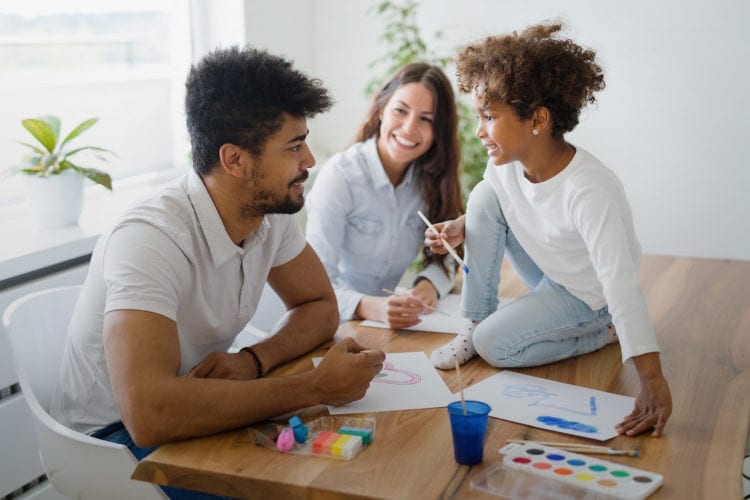 young family spending time together painting at the kitchen table