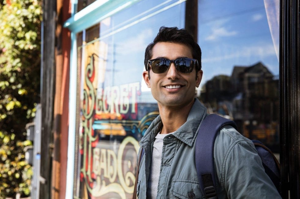 Man leaning on shop window wearing Invisalign an adult treatment for his person's clinical and smile goals