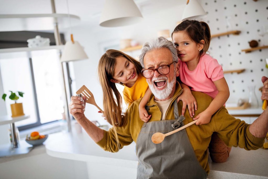 Grandpa and granddaughters playing and smiling in the kitchen of their Arden Arcade home