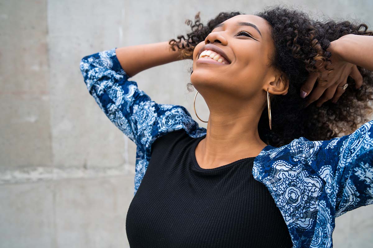 Very happy woman looking up with hands in her hair smiling a gorgeous smile