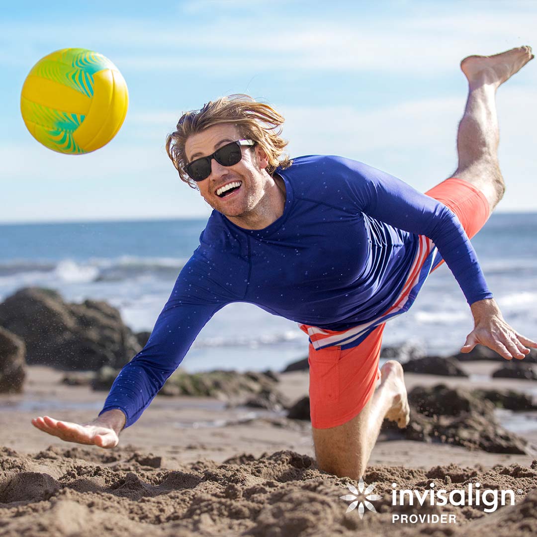 Active man playing beach volleyball while wearing Invisalign aligners during orthodontic treatment