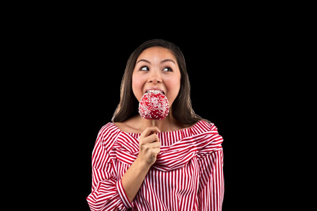 Teen girl eating a candy apple with Invisalign. Learn about the average cost of Invisalign treatment and how to make it affordable.