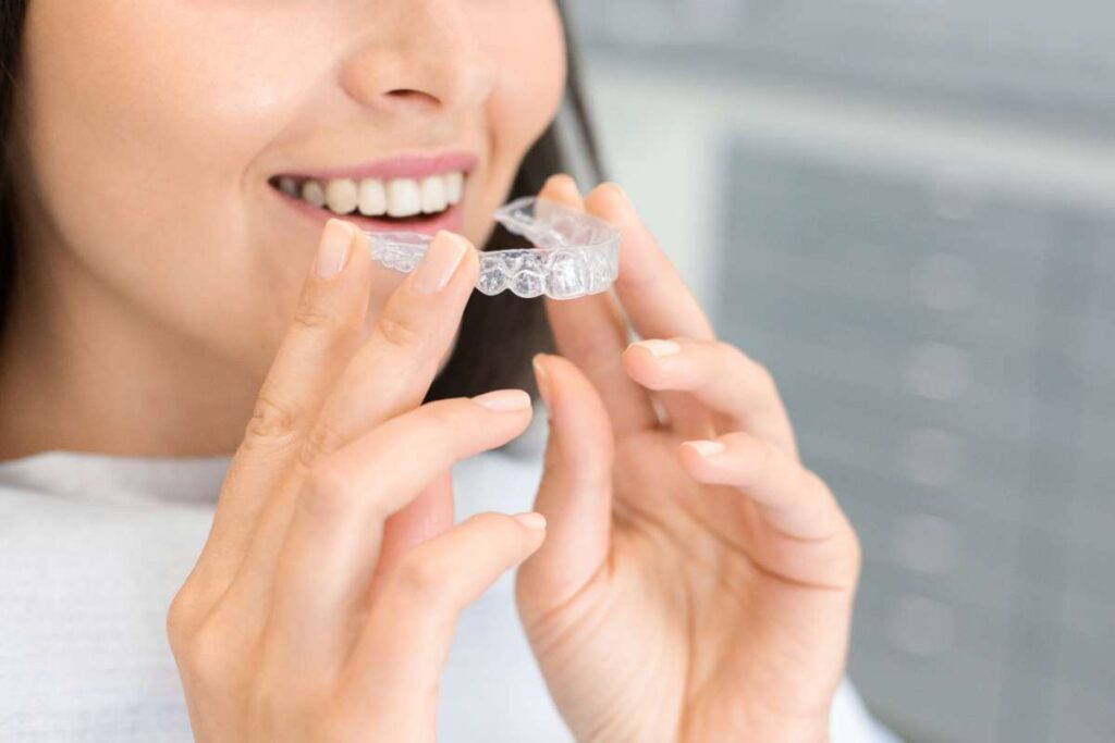 girl holding clear aligners to straighten her teeth - sm