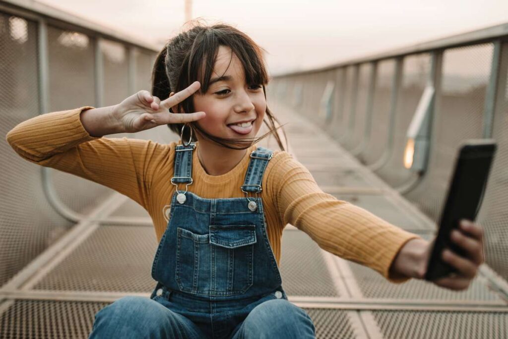 Funny girl taking selfie on smartphone on walkway - sm