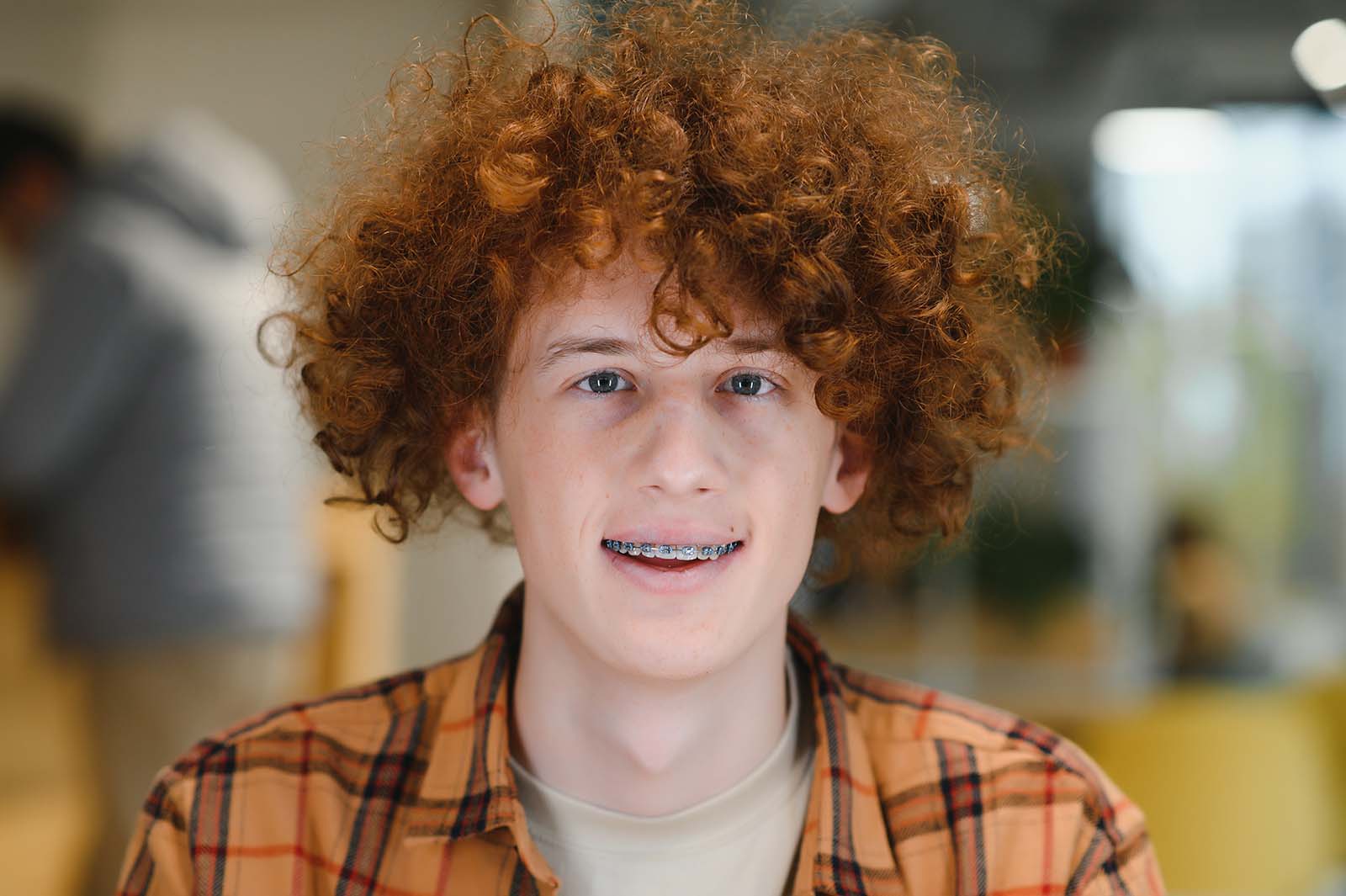 smiling teenage boy with curly hair wearing braces