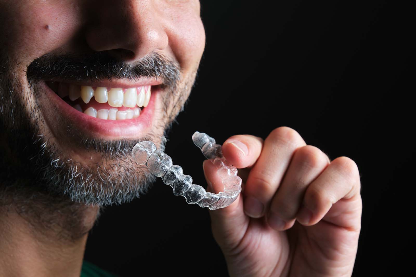 man inserting a clear aligner for his bottom teeth man inserting a clear aligner for his bottom teeth