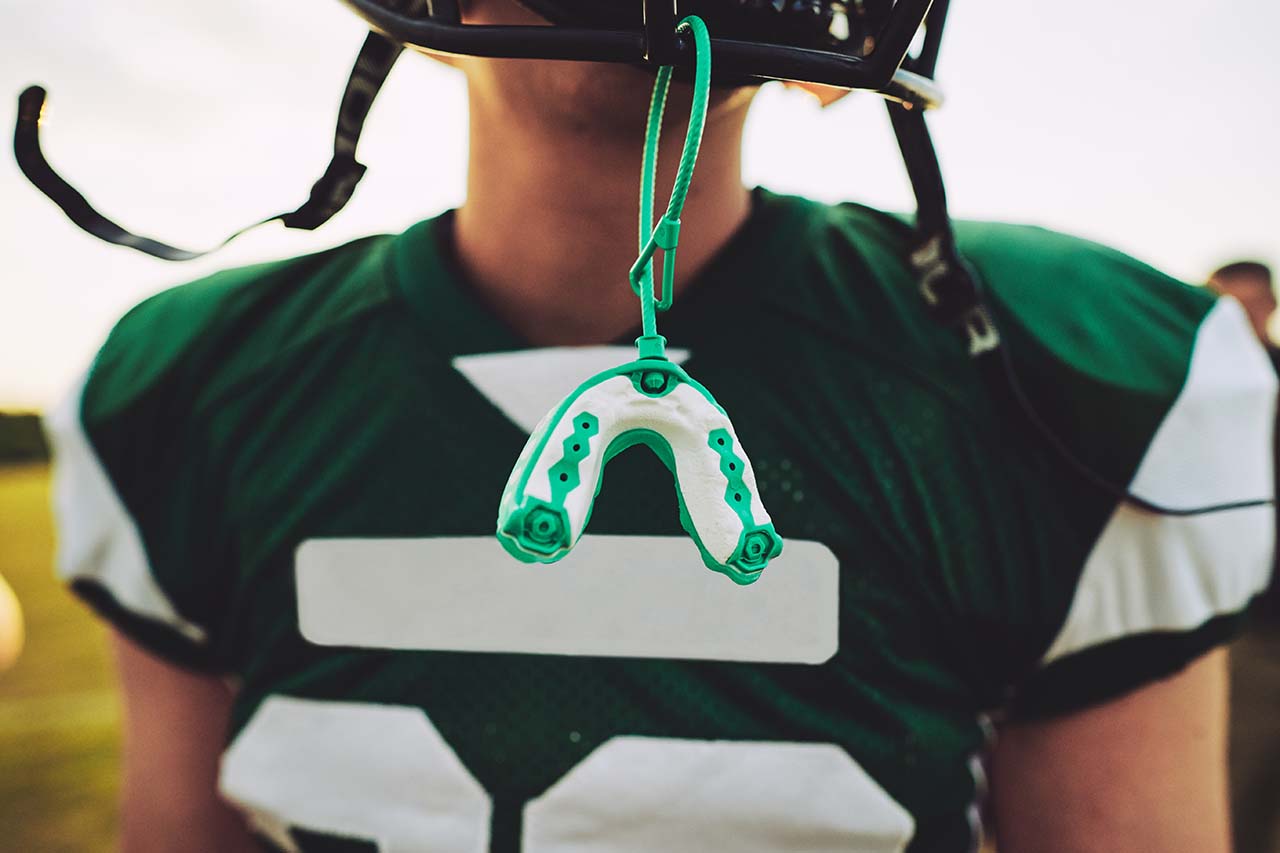 mouthguard hanging off the helmet of a football player