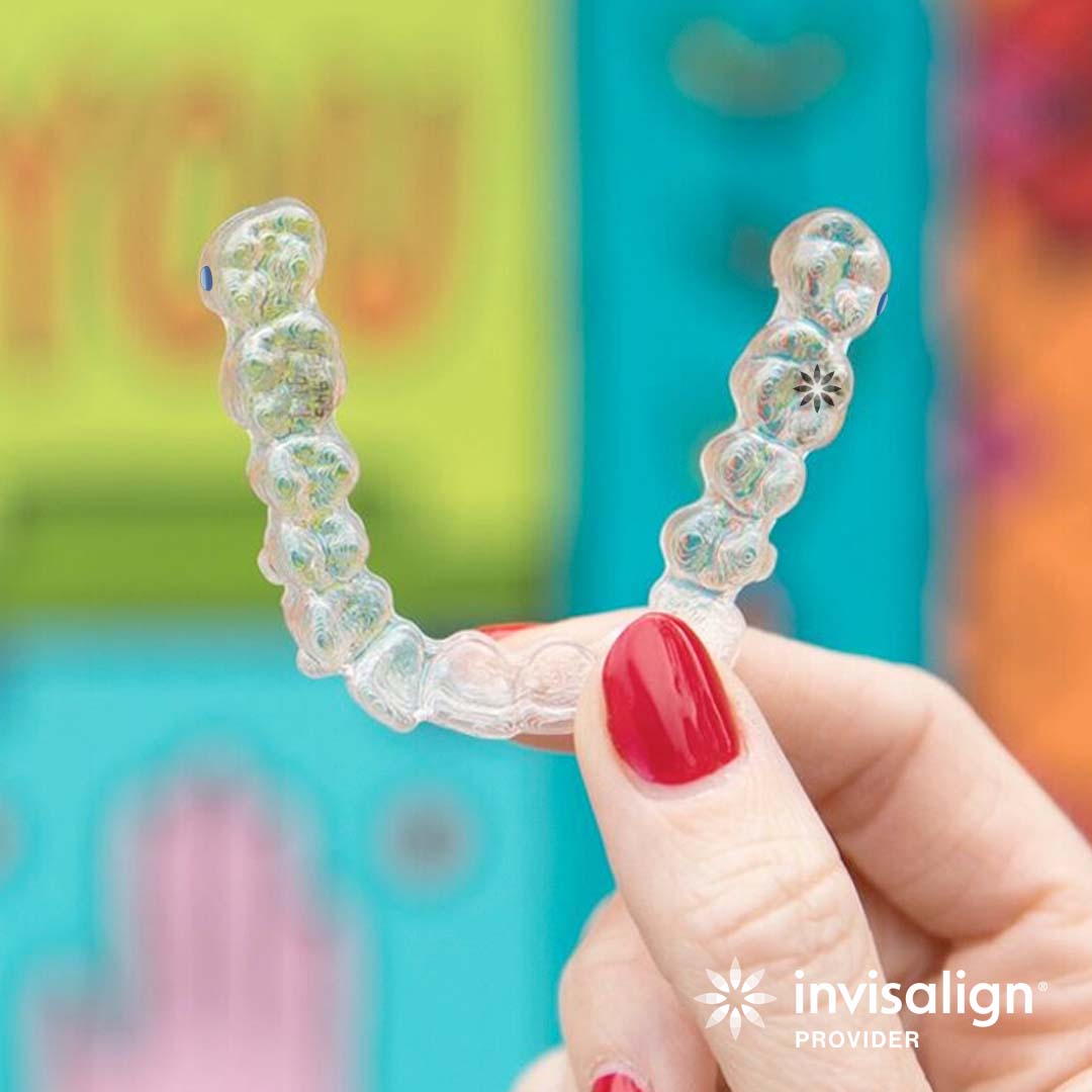 American River Orthodontics offers a free consultation Woman's hand holding a clear Invisalign aligner in front of a colorful background.