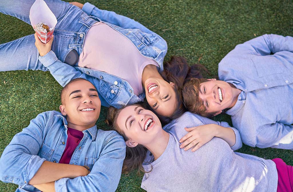 Invisalign for faster and less painful orthodontic treatment smiling teens wearing invisalign aligners laying down in the grass