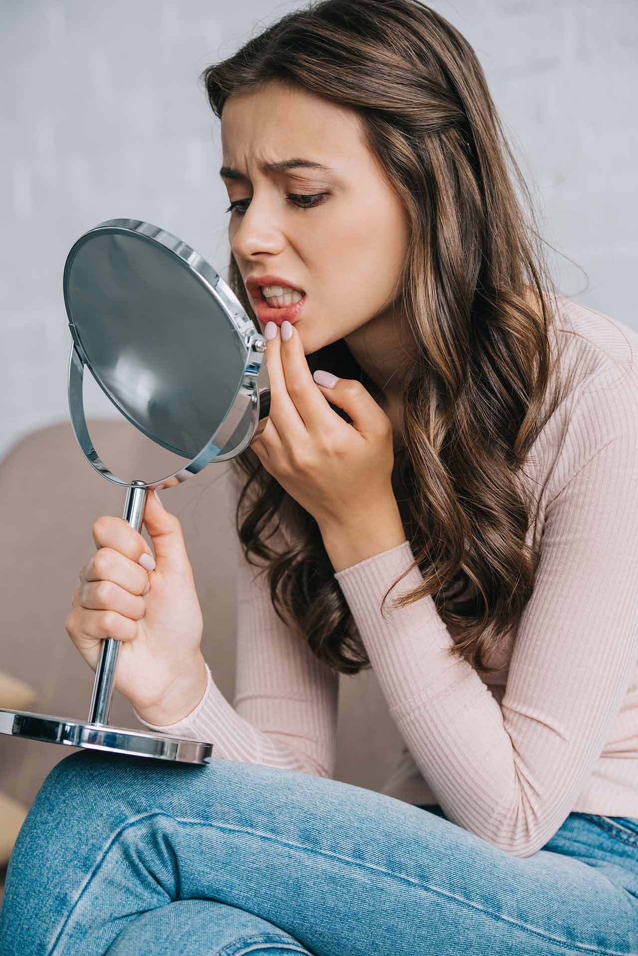 Young woman considering minor orthodontic treatment because her teeth have started shifting young woman checks out her teeth in the mirror
