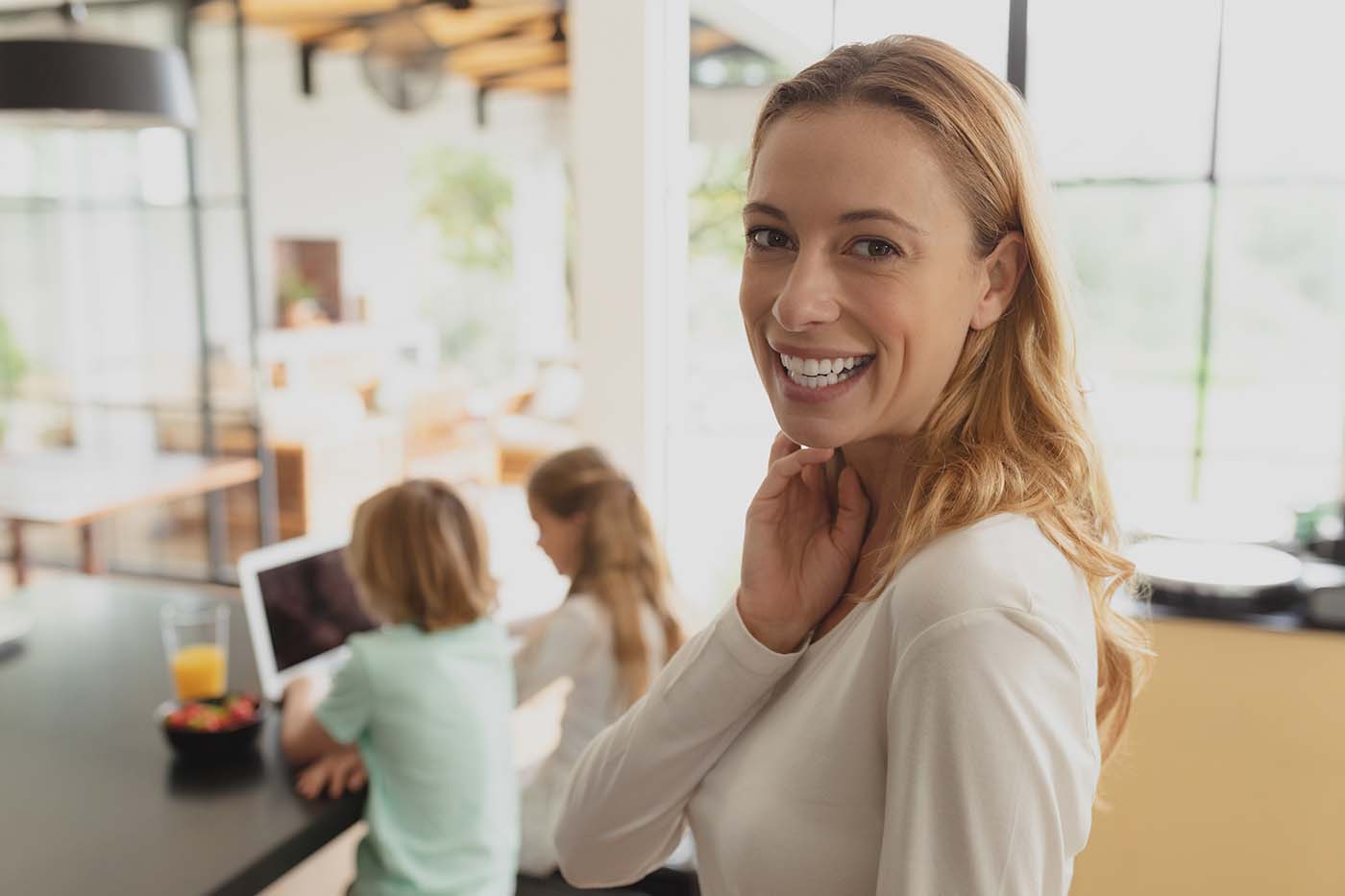 happy and confident mom with two young kids playing on laptop at the table Happy mother and children at a table using a laptop to find affordable orthodontic payment plans.